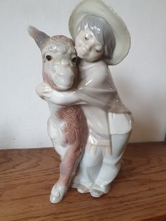 a ceramic figurine of a woman hugging a dog