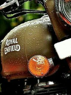 an old royal enfield motorcycle parked in the rain