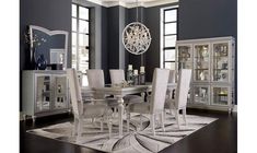 a dining room table with white chairs and a chandelier hanging from the ceiling