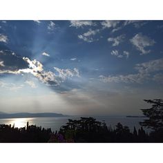 the sun shines brightly through clouds over trees and water in front of a body of water