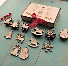 wooden christmas ornaments are sitting on a table next to a box with a red ribbon