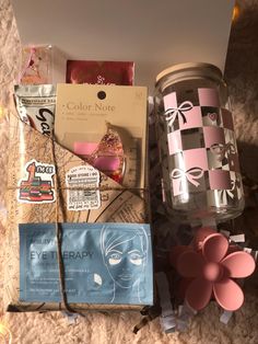 the contents of a beauty box laid out on top of a carpeted floor next to a candle and other items