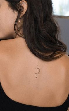 the back of a woman's neck with a small crescent tattoo on her left shoulder