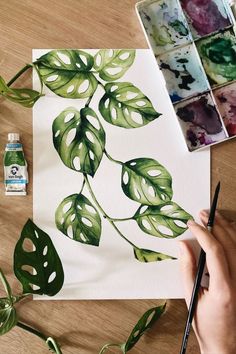 someone is painting leaves on paper with watercolors