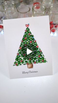 a card with a christmas tree on it sitting in front of some glass jars filled with candy