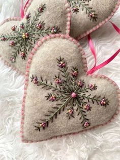 three heart shaped ornaments with pink bows on white fur