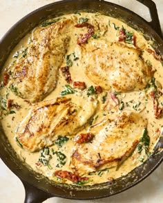 some chicken is cooking in a skillet on the stove top with cheese and spinach