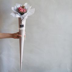 a person is holding a bouquet of flowers in an upside down umbrella shaped like a cone