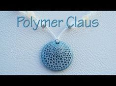 a blue pendant with the word polymer claus written on it and a white beaded cord