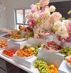 a table filled with lots of different types of food and flowers in vases on top of it