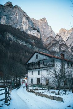 an old house in the mountains with snow on the ground