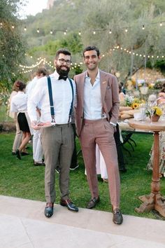 two men standing next to each other in front of a table with flowers on it