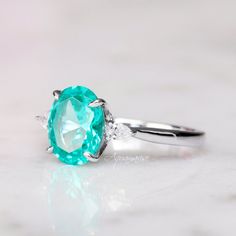 Gorgeous Paraiba Tourmaline Ring ►Made of solid sterling silver with rhodium finish (925) ►Accented With Simulated Diamonds (CZ) ►Average band width: 2 mm Center Stone: Paraiba Tourmaline Color: Turquoise Shape: Oval Measurements: 7.0 x 9.0 mm Carat Weight: 1.8 ct. (approx.) Gemstone creation: lab-grown Hardness: 7-7.5 (Mohs scale) ✓ 100% Nickel-Free ✓ Hypoallergenic ✓ Comfort Fit ✓ Free Ring Box ✓ Free USA Shipping Tourmaline Rings, Paraiba Tourmaline Ring, Paraiba Tourmaline, Sterling Silver Engagement Rings, Tourmaline Ring, Dream Engagement Rings, Silver Engagement Rings, Solid Gold Jewelry, October Birth Stone