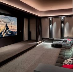 a home theater with two couches and a large screen on the wall in front of it