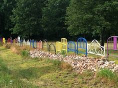 there are many different colored fences in the grass near trees and rocks on the side of the road