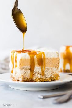 a spoon drizzling caramel sauce over a cheesecake on a white plate