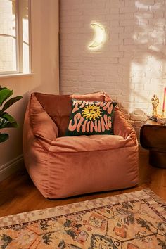 a living room with a large pink chair and rug on the floor next to a brick wall