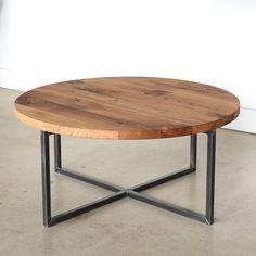 a wooden table sitting on top of a cement floor next to a white wall and black metal frame