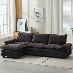 a living room with a sectional couch and white rug on the floor next to windows