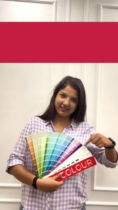 a woman is holding some color samples in her hands