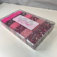 a box filled with lots of pink and purple glitters on top of a white table