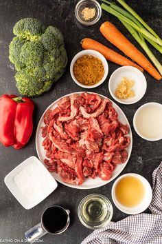 raw meat and vegetables laid out on a black counter top, including broccoli