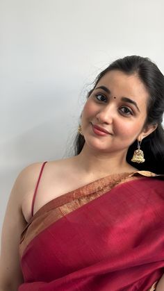 a woman wearing a red sari and gold earrings