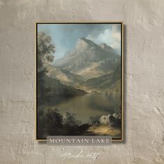 a painting hanging on the side of a wall with a mountain lake in front of it