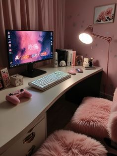 a desk with a computer monitor, keyboard and pink fur pillows on top of it