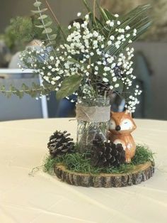 a vase filled with white flowers sitting on top of a wooden stump next to a pine cone