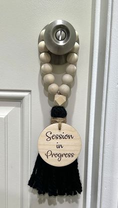 a door hanger that says season in progress with tassels hanging from it