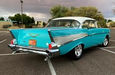 an old blue and white car parked in a parking lot