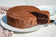 a chocolate cake on a white plate with a slice missing