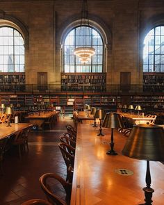 an empty library with tables and lamps in front of two large arched windowed windows