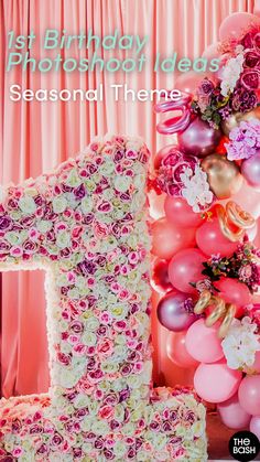 the number one is made out of flowers and balloons in front of a pink backdrop