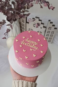 a pink birthday cake sitting on top of a table