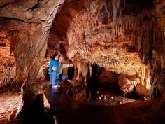 two people standing in the middle of a cave with lots of stalate formations