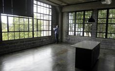 a person standing in an empty room with large windows