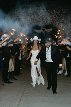 a bride and groom walk through sparklers at their wedding