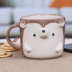 a mug with a bear face on it sitting next to crackers