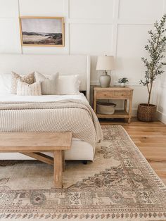 a large bed sitting on top of a wooden floor next to a dresser and lamp