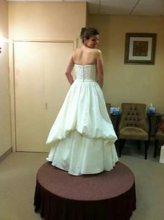 a woman in a wedding dress standing on a round table