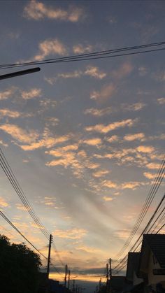 the sun is setting behind power lines and telephone poles in an urban area with houses