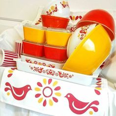 an assortment of colorful dishes and utensils in a tray on a white tablecloth