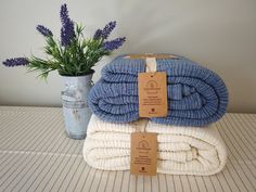 two blue and white towels stacked on top of each other next to a potted plant