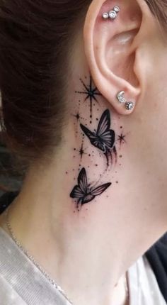 a woman's neck with two butterflies on it and stars behind her ear tattoo