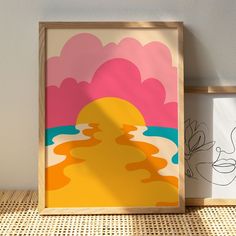 two framed pictures sitting next to each other on top of a wooden table with a painting in front of them