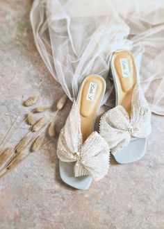 two pairs of shoes sitting on top of a floor next to a bag and some dry grass