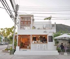 the outside of a restaurant with people sitting at tables and umbrellas in front of it