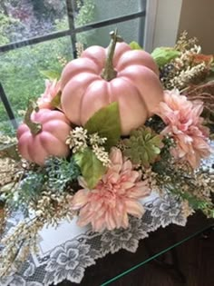 a vase filled with flowers and pumpkins sitting on top of a table next to a window